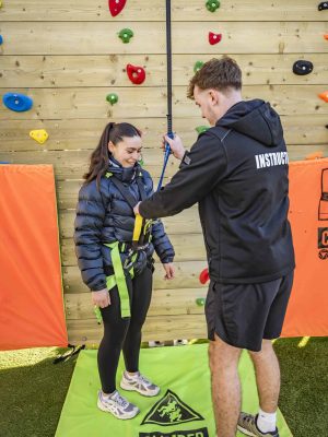 Climber fitted with safety harness for climbing wall.